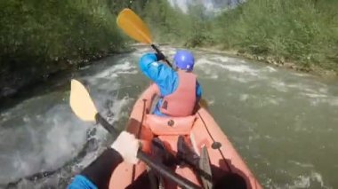 Bahar zamanı dağ nehrinde rafting yapan iki kişi. Olağanüstü profesyonel su sporu