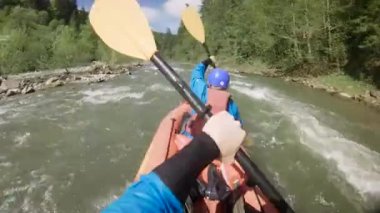 Bahar zamanı dağ nehrinde rafting yapan iki kişi. Olağanüstü profesyonel su sporu