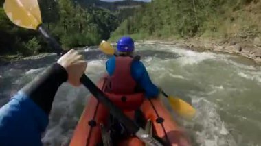 Bahar zamanı dağ nehrinde rafting yapan iki kişi. Olağanüstü profesyonel su sporu