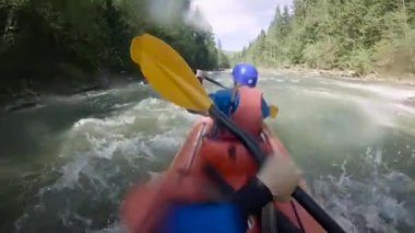 Bahar zamanı dağ nehrinde rafting yapan iki kişi. Olağanüstü profesyonel su sporu