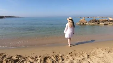 Mercan koyunda yürüyen beyaz elbiseli güzel sarışın kadın. Kıbrıs 'a seyahat. Özgürlük yaz konsepti