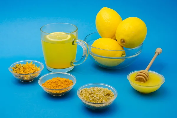 Lemon and healthy tea with turmeric and honey for better immunity system. Natural products on blue background
