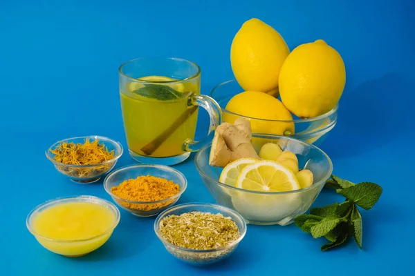 Lemon and healthy tea with turmeric and honey for alternative medicine treatment and immunity system. Natural products on blue background