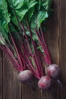 Kırsal ahşap arka planda yaprakları olan taze pancar kökünü kapat.