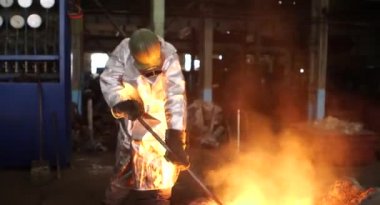 Dökümhanede sıkı çalışma. Erimiş çelik dökülüyor. Sıvı çelik dökülüyor. Erimiş metal dökümü, metalürji, çelik döküm dökümü. Çelik imalatı