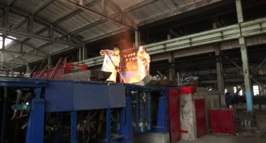 Dökümhanede sıkı çalışma. Erimiş çelik dökülüyor. Sıvı çelik dökülüyor. Erimiş metal dökümü, metalürji, çelik döküm dökümü. Çelik imalatı