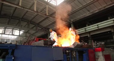 Dökümhanede sıkı çalışma. Erimiş çelik dökülüyor. Sıvı çelik dökülüyor. Erimiş metal dökümü, metalürji, çelik döküm dökümü. Çelik imalatı