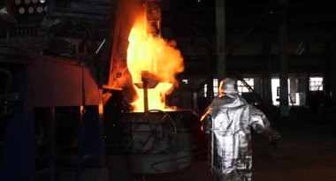 Dökümhanede sıkı çalışma. Erimiş çelik dökülüyor. Sıvı çelik dökülüyor. Erimiş metal dökümü, metalürji, çelik döküm dökümü. Çelik imalatı