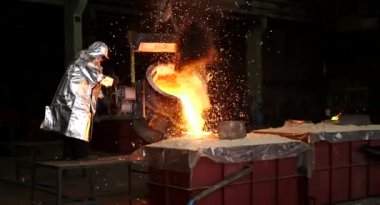 Dökümhanede sıkı çalışma. Erimiş çelik dökülüyor. Sıvı çelik dökülüyor. Erimiş metal dökümü, metalürji, çelik döküm dökümü. Çelik imalatı