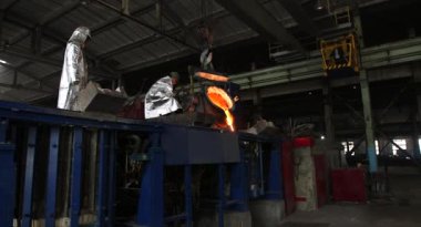 Dökümhanede sıkı çalışma. Erimiş çelik dökülüyor. Sıvı çelik dökülüyor. Erimiş metal dökümü, metalürji, çelik döküm dökümü. Çelik imalatı