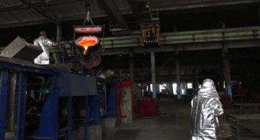 Dökümhanede sıkı çalışma. Erimiş çelik dökülüyor. Sıvı çelik dökülüyor. Erimiş metal dökümü, metalürji, çelik döküm dökümü. Çelik imalatı