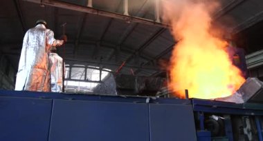 Dökümhanede çok çalışmak. Çelik fabrikasında metal eritme fırını. Erimiş metal dökümü, metalürji, çelik döküm dökümü. Çelik imalatı