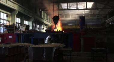 Dökümhanede çok çalışmak. Çelik fabrikasında metal eritme fırını. Erimiş metal dökümü, metalürji, çelik döküm dökümü. Çelik imalatı