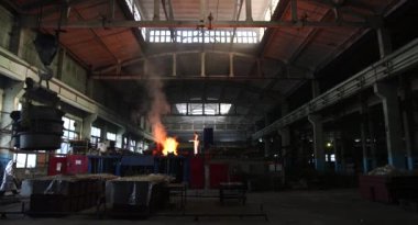 Dökümhanede çok çalışmak. Çelik fabrikasında metal eritme fırını. Erimiş metal dökümü, metalürji, çelik döküm dökümü. Çelik imalatı