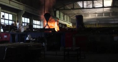 Dökümhanede çok çalışmak. Çelik fabrikasında metal eritme fırını. Erimiş metal dökümü, metalürji, çelik döküm dökümü. Çelik imalatı