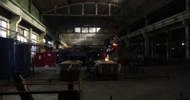 Dökümhanede çok çalışmak. Çelik fabrikasında metal eritme fırını. Erimiş metal dökümü, metalürji, çelik döküm dökümü. Çelik imalatı