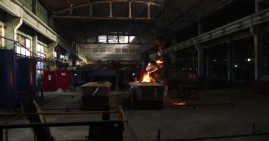 Dökümhanede çok çalışmak. Çelik fabrikasında metal eritme fırını. Erimiş metal dökümü, metalürji, çelik döküm dökümü. Çelik imalatı