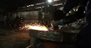 Erkek el nargile parçaları açısı öğütücü ile keser. Bir çelik inşaat alanında kıvılcım sıçraması ile kesme. Metal açılı taşlama kesim sırasında kıvılcım