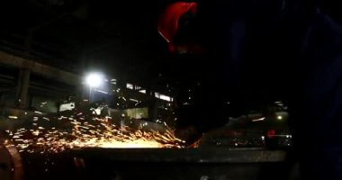Erkek el nargile parçaları açısı öğütücü ile keser. Bir çelik inşaat alanında kıvılcım sıçraması ile kesme. Metal açılı taşlama kesim sırasında kıvılcım