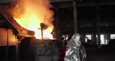 Dökümhanede çok çalışmak. Çelik fabrikasında metal eritme fırını. Erimiş metal dökümü, metalürji, çelik döküm dökümü. Çelik imalatı
