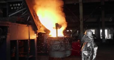 Dökümhanede çok çalışmak. Çelik fabrikasında metal eritme fırını. Erimiş metal dökümü, metalürji, çelik döküm dökümü. Çelik imalatı