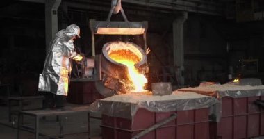 Dökümhanede çok çalışmak. Çelik fabrikasında metal eritme fırını. Erimiş metal dökümü, metalürji, çelik döküm dökümü. Çelik imalatı