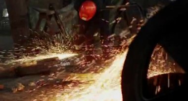 Metal açı öğütücüsünün kesilmesi sırasında kıvılcımlar. Parlayan kıvılcım bir sürü öğütücü dönen disk etrafında uçar. Pırıl pırıl bir arka plan. Metal kesim