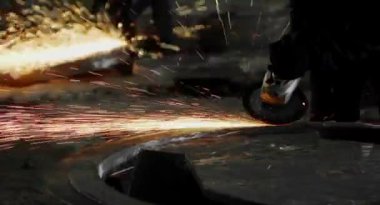 Metal açı öğütücüsünün kesilmesi sırasında kıvılcımlar. Parlayan kıvılcım bir sürü öğütücü dönen disk etrafında uçar. Pırıl pırıl bir arka plan. Metal kesim