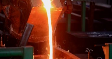 Dökümhanede sıkı çalışma. Erimiş çelik dökülüyor. Sıvı çelik dökülüyor. Erimiş metal dökümü, metalürji, çelik döküm dökümü. Çelik imalatı