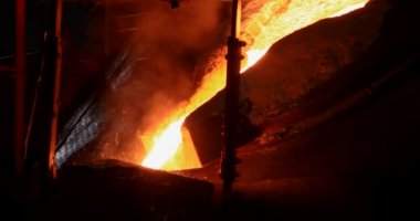 Dökümhanede sıkı çalışma. Erimiş çelik dökülüyor. Sıvı çelik dökülüyor. Erimiş metal dökümü, metalürji, çelik döküm dökümü. Çelik imalatı