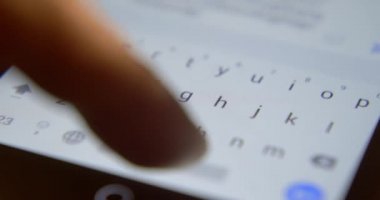 Genç adam ev ödevi yaparken akıllı telefon kullanıyor. Erkek öğrenci evde ders çalışıyor ve cep telefonuyla mesajlaşıyor, cep telefonuna mesaj yazıyor. Yakın plan.