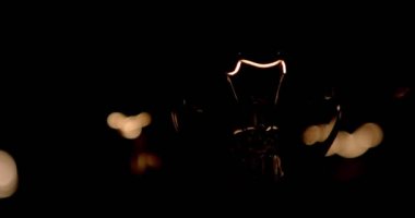 Tel üzerinde tungsten filament sallanan parlak lamba. Işık yanıp sönüyor. Ampulden gelen bir ışık. Ampul yakın plan.