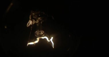 Tel üzerinde tungsten filament sallanan parlak lamba. Işık yanıp sönüyor. Ampulden gelen bir ışık. Ampul yakın plan.