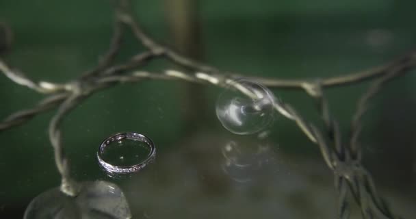 Состав двух свадебных серебряных колец за столом. Мужское кольцо катится к другому. . — стоковое видео