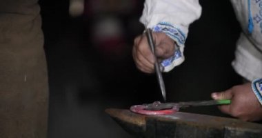 Forge atölyesinde sıcak kırmızı metal çubuğu şekillendirmek için çekiç makinesini kullanarak, yakın çekim görünümü. Küçük bir plaka ve otomatik çekiç üzerinde tutma kiriş üstüne isabet ediyor. Metalürjik üretimde metal dövme.