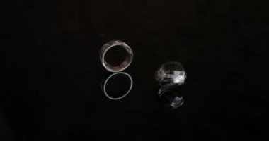 Siyah arka planda altın nişan yüzükleri. Alyanslar. Bir nikah gününde iki muhteşem alyans. Masada iki alyans var..