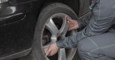 Yakışıklı sürücü unscrewing araba tekerlek üzerinde yol kenarı düz lastik değiştirmek için yol kenarında Pnömatik anahtarı tarafından. Adam araba tekerlek lastiği yolculuk sırasında değiştirdikten sonra anahtar ile uygun rahat kıyafetler.