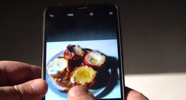 Jongeman fotografeert lunch in restaurant met de telefoon. Een jonge man neemt foto van taarten eten op smartphone, fotograferen maaltijd met mobiele camera. — Stockvideo