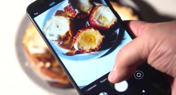 若い男が電話でレストランで昼食を撮っている。スマホでケーキの食べ物を写真に撮り、携帯カメラで食事を撮る青年. — ストック動画