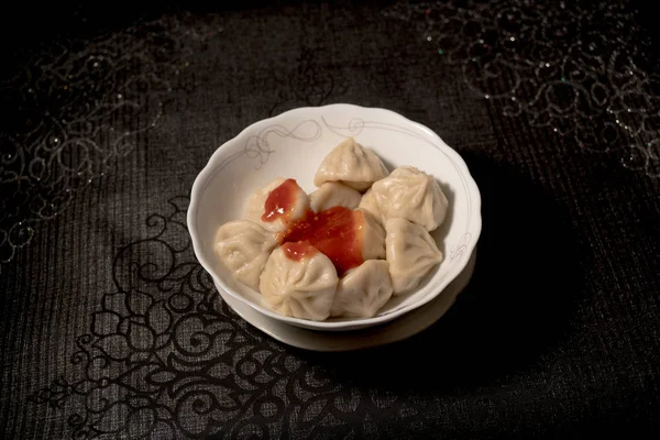 Close-up van draaiende plaat van heerlijke khinkali dumplings gekruid met Chili peper — Stockfoto