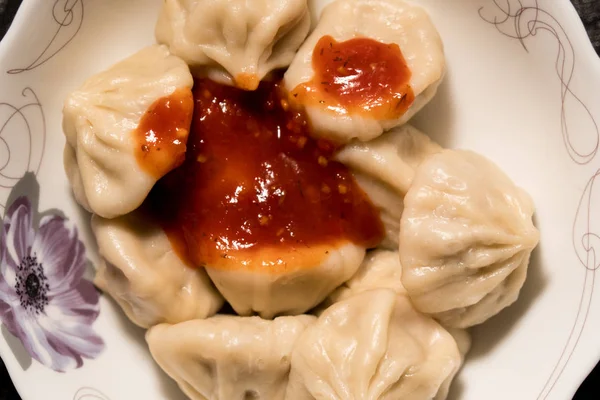 Close-up van draaiende plaat van heerlijke khinkali dumplings gekruid met Chili peper — Stockfoto