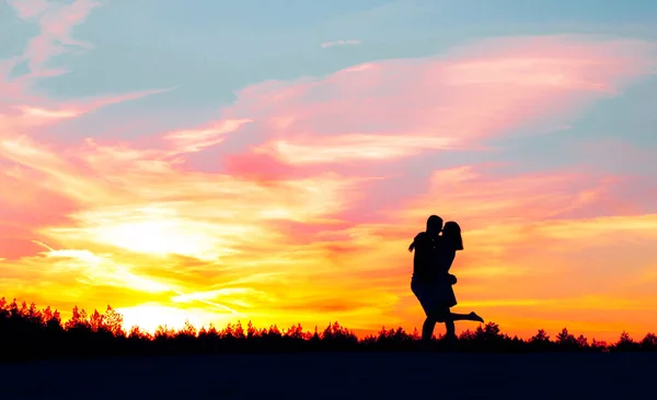 Uma silhueta de uma menina se aproximando de seu amado cara e abraça-o contra o pano de fundo do pôr do sol e cabras . — Fotografia de Stock