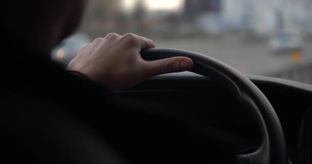 Un primer plano de las manos de un hombre sosteniendo un volante del coche desde el interior de un coche que viaja por una carretera . — Vídeos de Stock