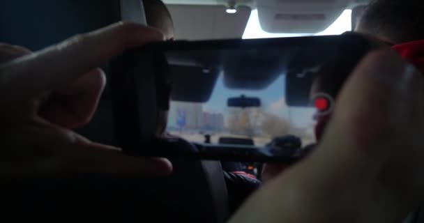Bir adam araba yolculuğu sırasında cep telefonundan bir video kaydediyor. Ön camdan yol manzarası.. — Stok video