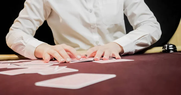 Dealer sitting in a casino at table while holding and distributing cards