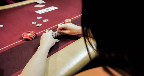 Dealer sitting in a casino at table while holding and distributing cards