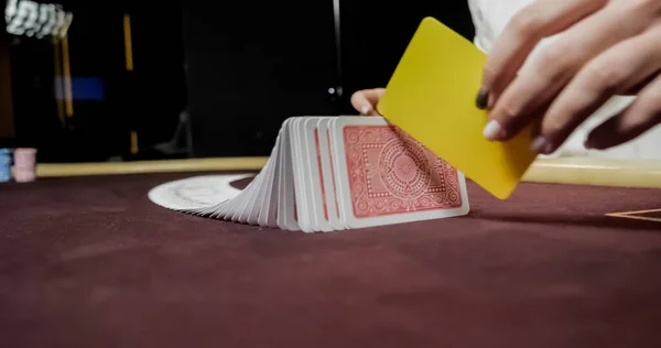 坐在一家赌场在桌上同时持有并分发卡的经销商 — 图库照片