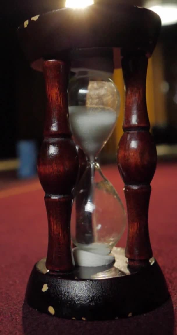 Vertical video for phones and tablets. Hourglass on a red table — Stock Video