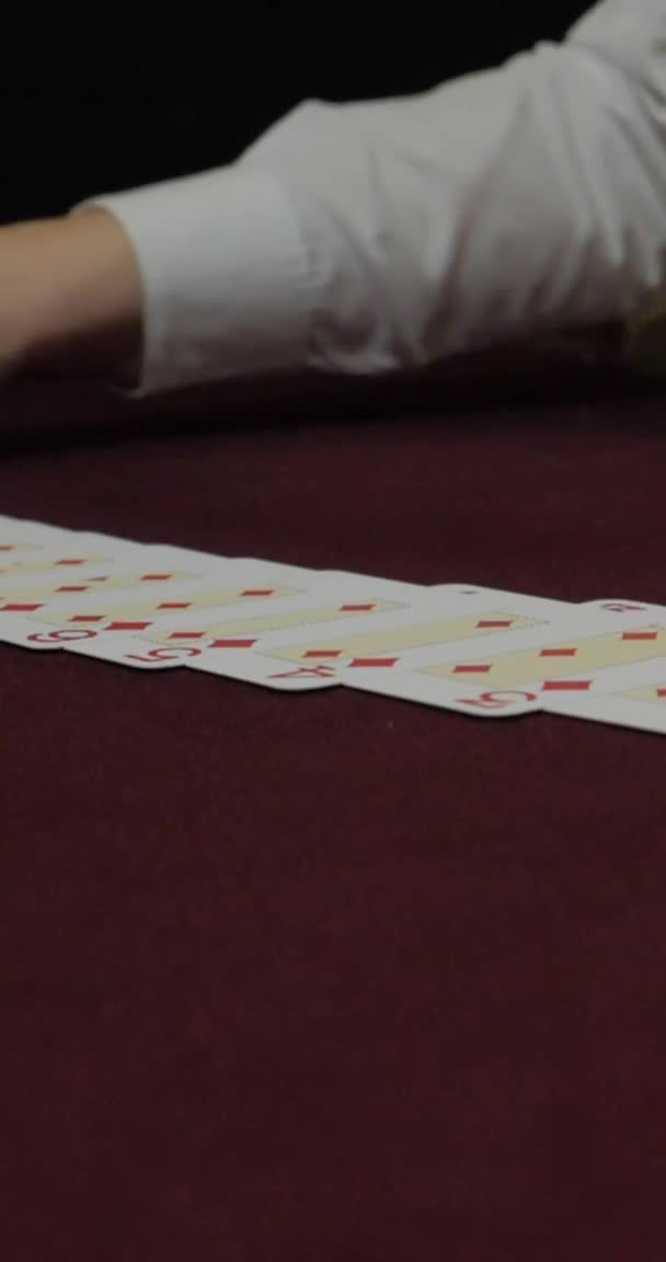 Vertikales Video für Telefone und Tablets. Dealer sitzt in einem Casino am Tisch, während er Karten hält und verteilt — Stockvideo