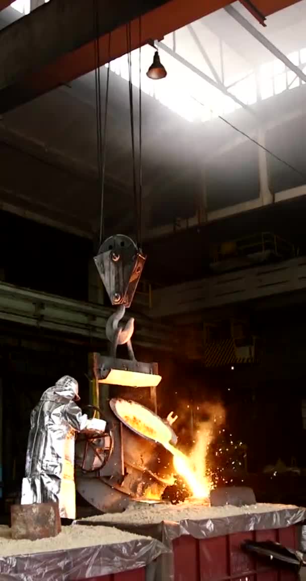 Вертикальное видео для телефонов и планшетов. Плавка оранжевого металла на металлургическом заводе. Жидкое железо из ладьи — стоковое видео